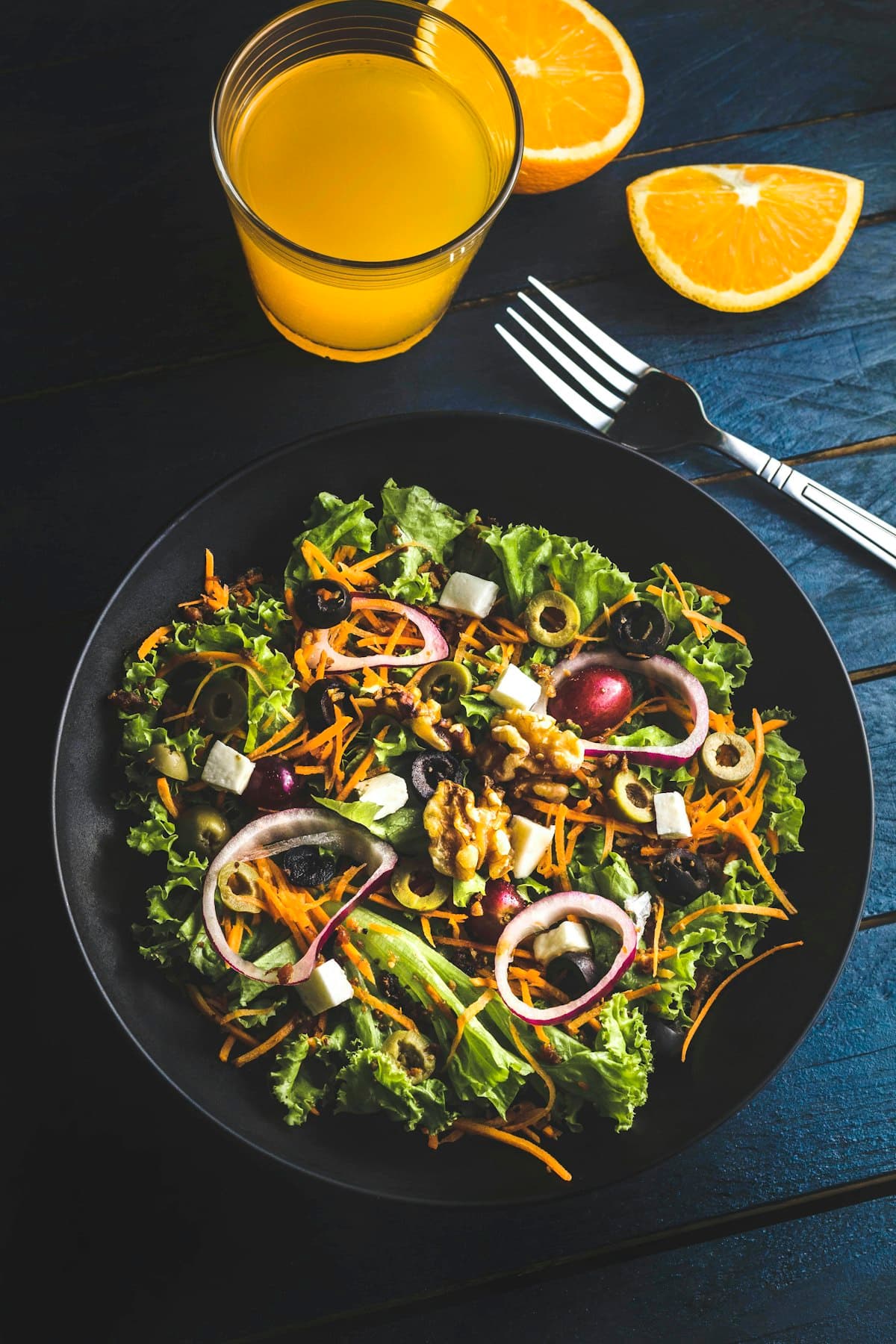 Grande salade colorée dressée en assiette noire
